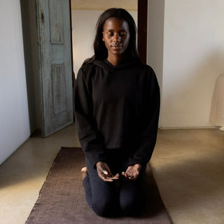 woman meditating on RItuil yoga rug and meditation seat