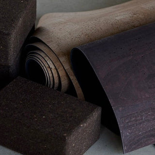 cork yoga mats and cork block rolled up against stone 