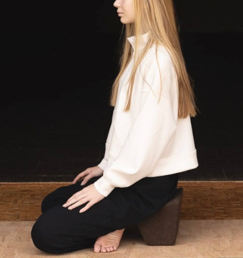 woman sitting on rituil natural cork mat and natural cork block meditating.