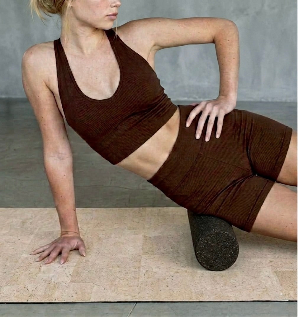 woman using Rituil cork massage roller on cork. yoga mat