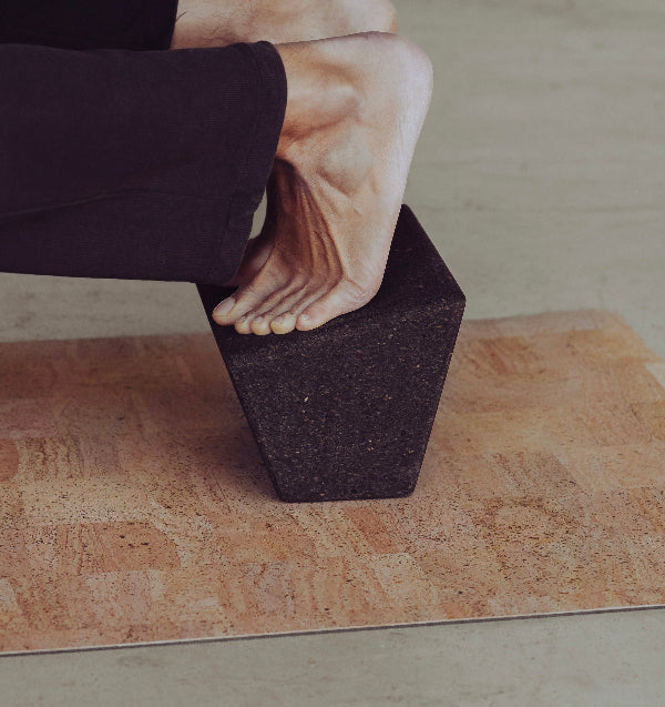 man practicing on rituil non slip non toxic cork yoga mat with rituil block in supported pigeon pose 