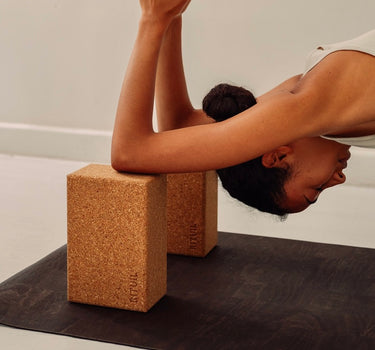 Rituil sustainable natural brown cork leather yoga mat featuring a non-slip, non-toxic, pvc free, with natural cork yoga blocks and woman practicing yoga 