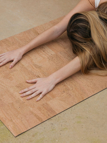 Rituil sustainable natural tan cork leather yoga mat featuring a non-slip, non-toxic, pvc free, with woman in childs pose