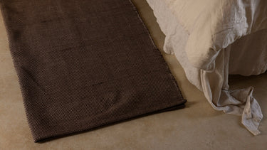 restorative cotton yoga rug on floor next to bed