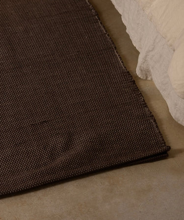 restorative cotton yoga rug on floor next to bed