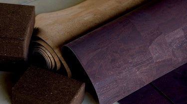 rolled up cork yoga mat and dark cork yoga blocks on concrete floor