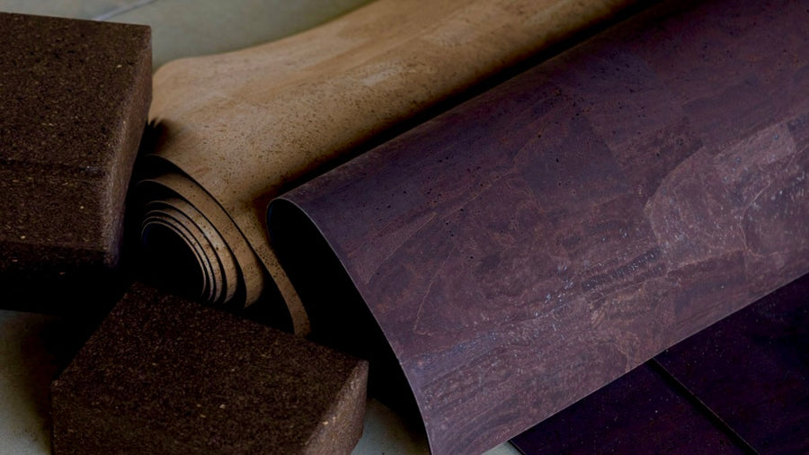 rolled up cork yoga mat and dark cork yoga blocks on concrete floor