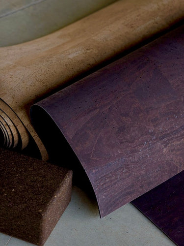 Rolled up cork yoga mat and cork blocks on concrete floor