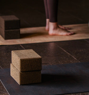 Rituil sustainable natural brown and tan cork leather yoga mats featuring a non-slip, non-toxic, pvc free surface laying on floor with cork yoga blocks and woman standing on mats