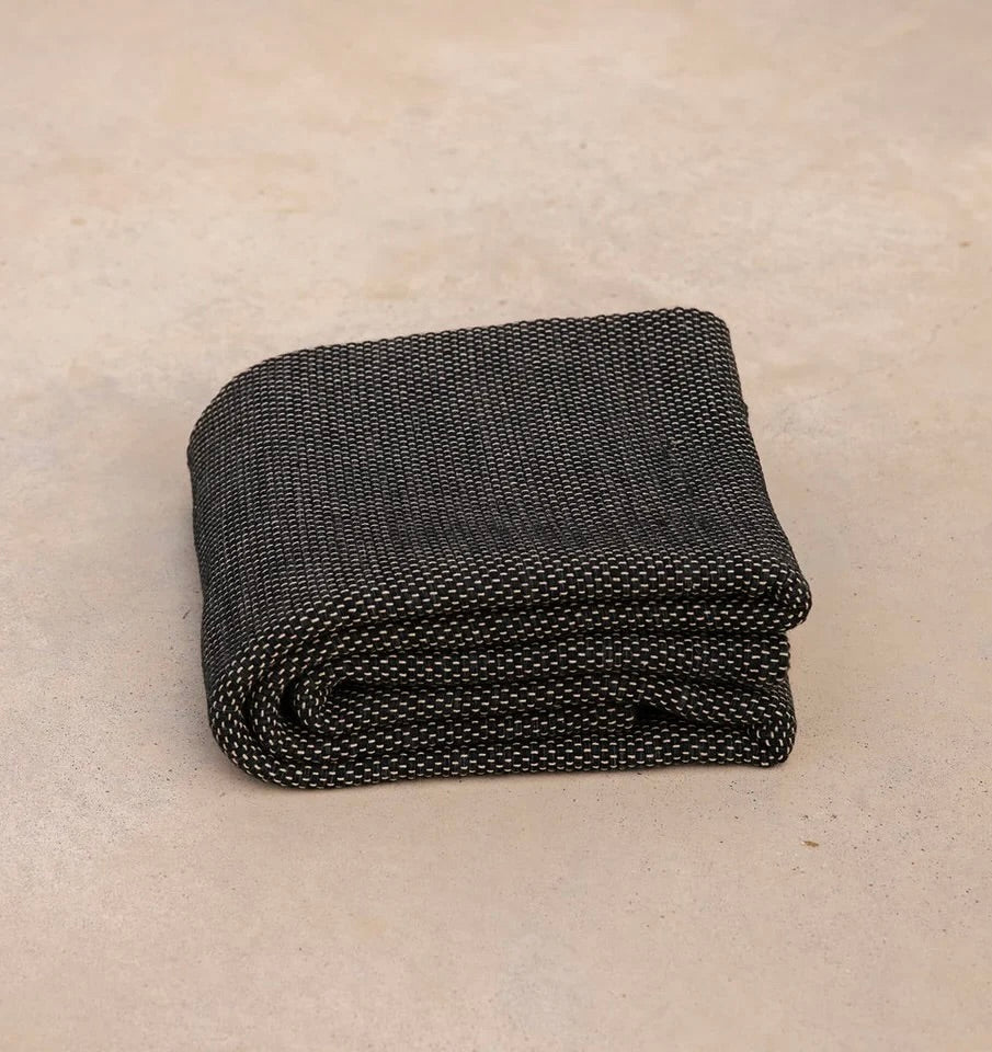⁠Heavyweight and oversized sustainable recycled cotton yoga rug in black folded on a studio floor. #color_ash