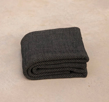 ⁠Heavyweight and oversized sustainable recycled cotton yoga rug in black folded on a studio floor. #color_ash