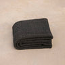 ⁠Heavyweight and oversized sustainable recycled cotton yoga rug in black folded on a studio floor. #color_ash