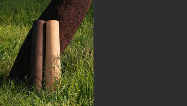 Rituil cork yoga mats rolled up against tree in earth and sand colors