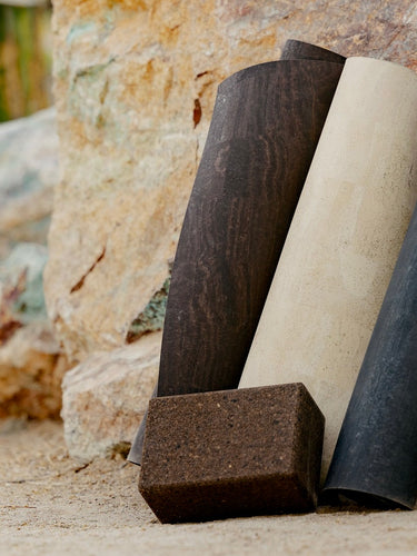 rolled up rituil cork yoga mats and block on rocks