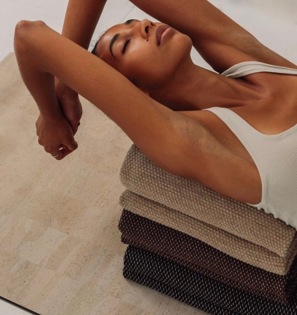 woman in heart opening pose on extra long and extra thick cream cork yoga mat and cotton yoga rugs