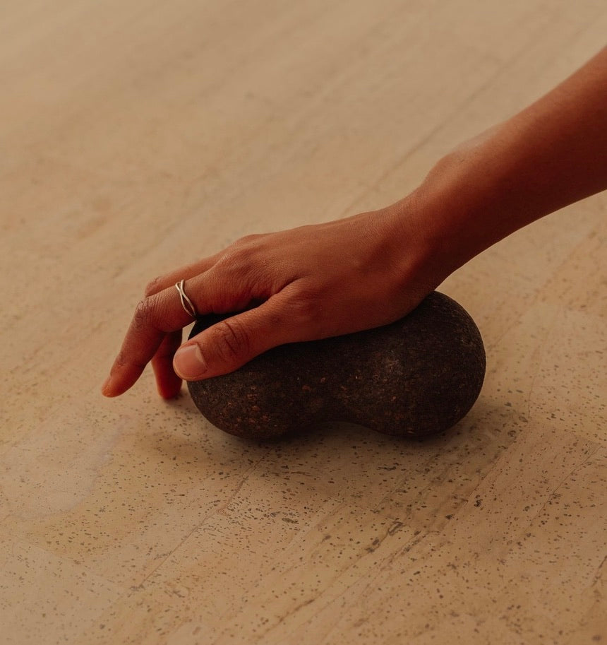 Rituil sustainable Portuguese cork massge peanut for yoga, Pilates core workouts, and deep tissue muscle recovery shown wiht womans hand pressing into peanut on cork yoga mat