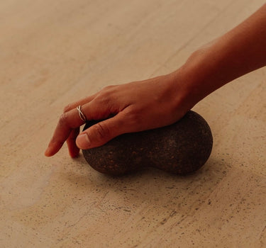 Rituil sustainable Portuguese cork massge peanut for yoga, Pilates core workouts, and deep tissue muscle recovery shown wiht womans hand pressing into peanut on cork yoga mat