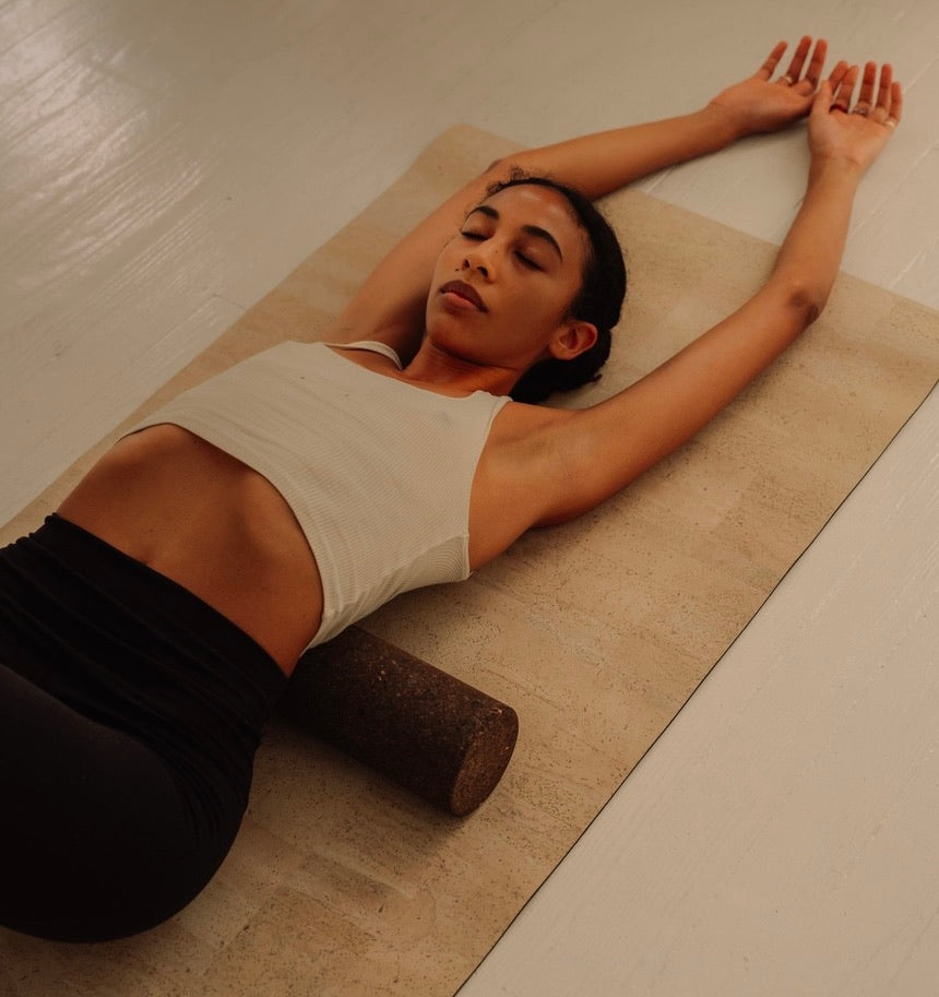 Woman practicing on Rituil sustainable Portuguese cork massge roller for deep tissue muscle recovery shown on top of cork yoga mat
