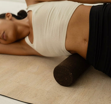 Woman practicing on Rituil sustainable Portuguese cork massge roller for deep tissue muscle recovery shown on top of cork yoga mat