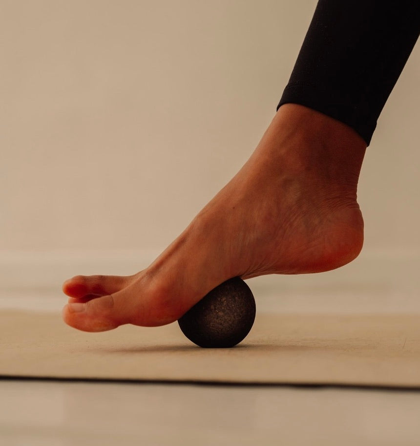 Rituil sustainable Portuguese cork massage ball pressing into woman foot on top of cork yoga mat