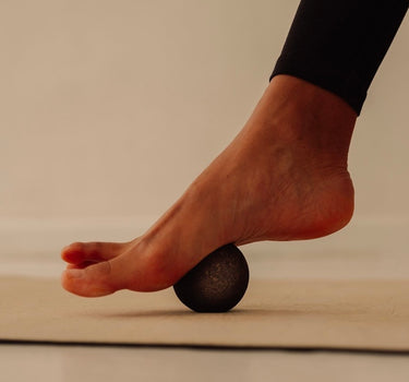 Rituil sustainable Portuguese cork massage ball pressing into woman foot on top of cork yoga mat
