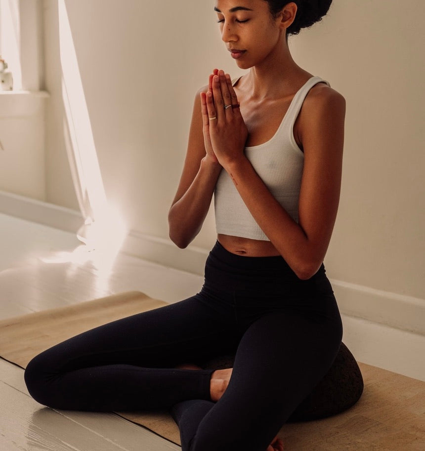 woman sitting in meditation pose on Rituil cork meditation seat and cork yoga mat