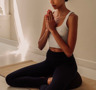 woman sitting in meditation pose on Rituil cork meditation seat and cork yoga mat