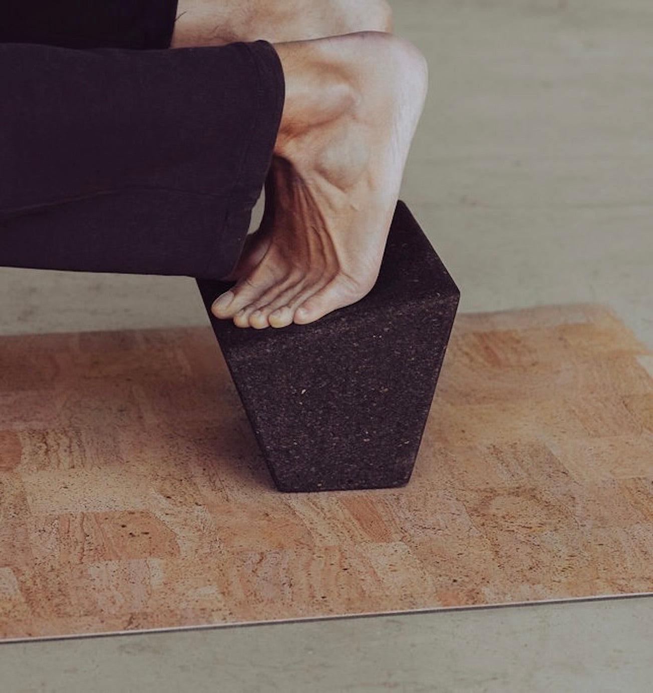 man with feet on rituil cork block on top of non slip cork yoga mat
