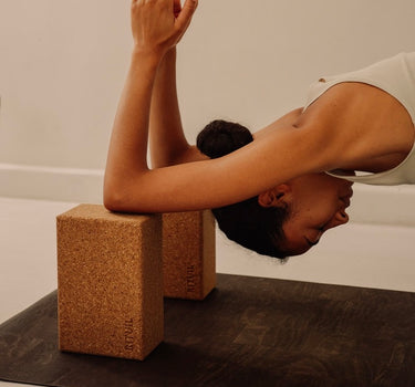 Rituil sustainable natural brown cork leather yoga mat featuring a non-slip, non-toxic, pvc free, with natural cork yoga blocks and woman practicing yoga 