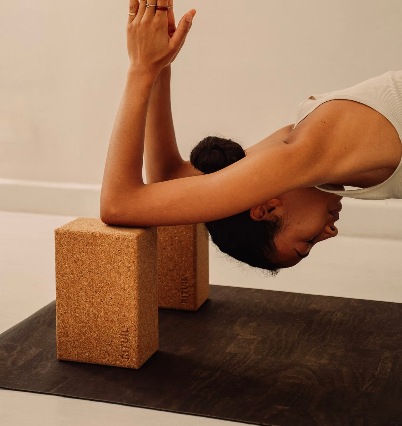 Rituil sustainable natural brown cork leather yoga mat featuring a non-slip, non-toxic, pvc free, with natural cork yoga blocks and woman practicing yoga 