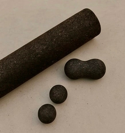 cork massage roller, peanut and spheres in brown on concrete floor