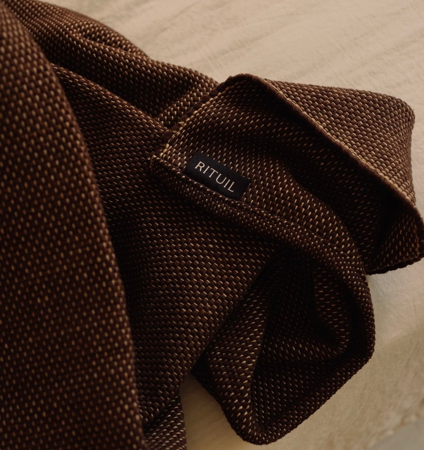 restorative yoga rug that is heavyweight and oversized and sustainable made with recycled cotton on bed. #color_earth
