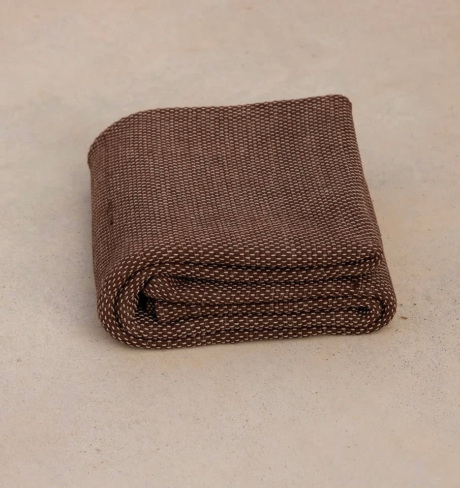 Oversized sustainable recycled cotton restorative yoga rug in brown color from Rituil folded on studio floor #color_earth