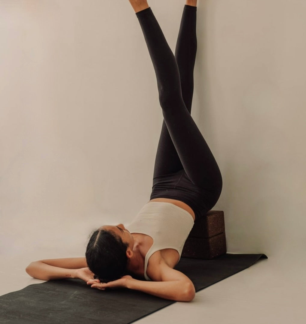 woman in legs up the wall yoga pose on extra long and extra thick brown cork yoga mat with cork blocks 