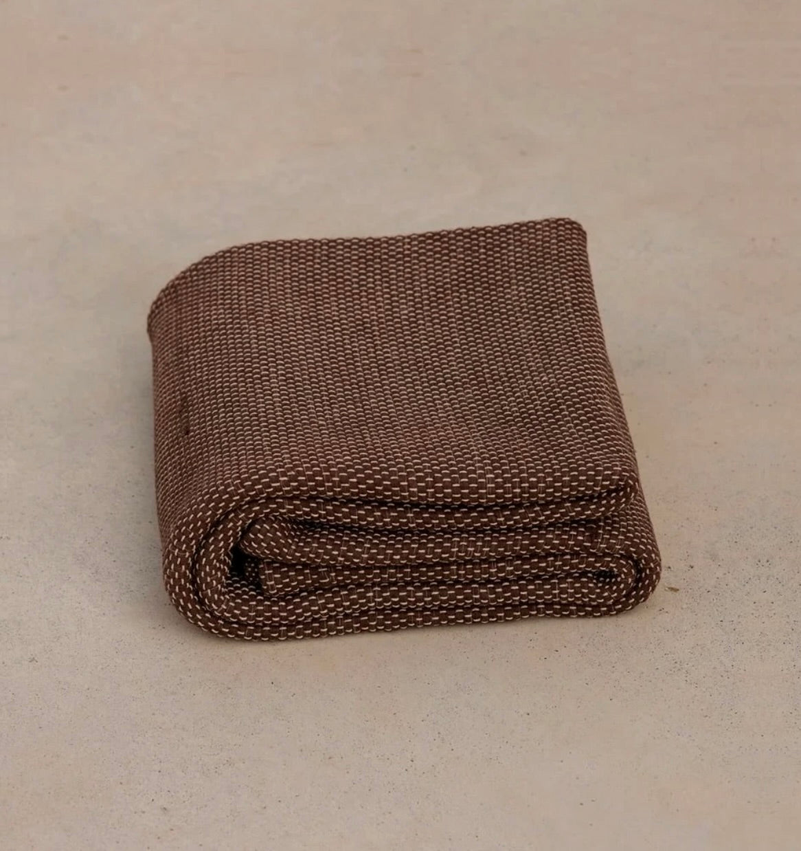 brown non toxic restorative yoga rug  folded on concrete floor #color_earth