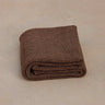 brown non toxic restorative yoga rug  folded on concrete floor #color_earth
