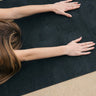 woman in childs pose on Rituil™ ash or black cork yoga mat #color_ash