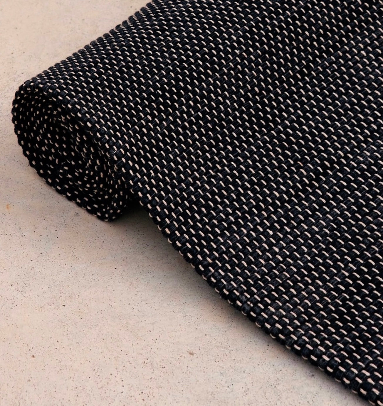 close up image of rolled Rituil™ yoga recycled cotton rug in ash or black color #color_ash