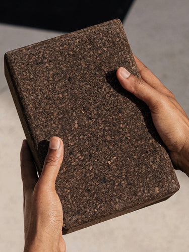 womans hands holding earth or brown colored yoga block #color_earth