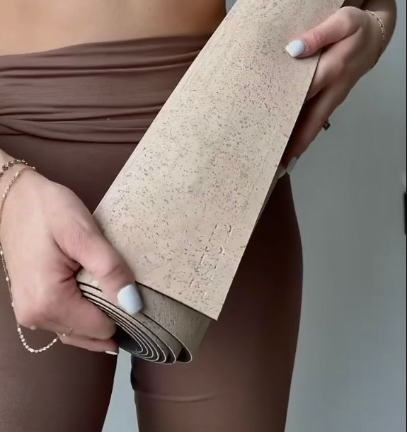 woman holding  rituil non-slip, non-toxic cream cork leather yoga mat in yoga studio #color_bone
