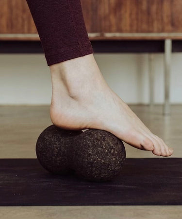 woman rolling foot on cork massage peanut