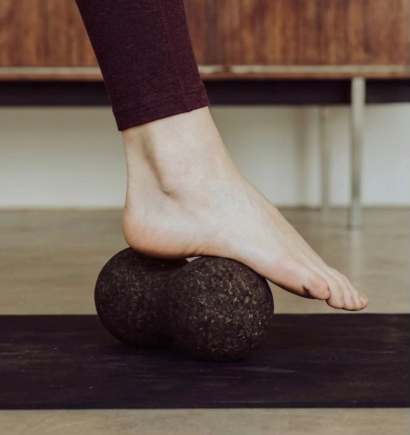 woman rolling foot on cork massage peanut