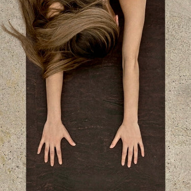 womans hands in childs pose on Rituil earth or brown colored cork yoga mat #color_earth