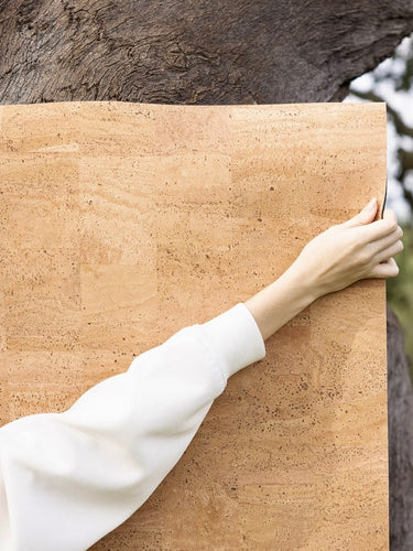 woman holding natural cork yoga mat against tree