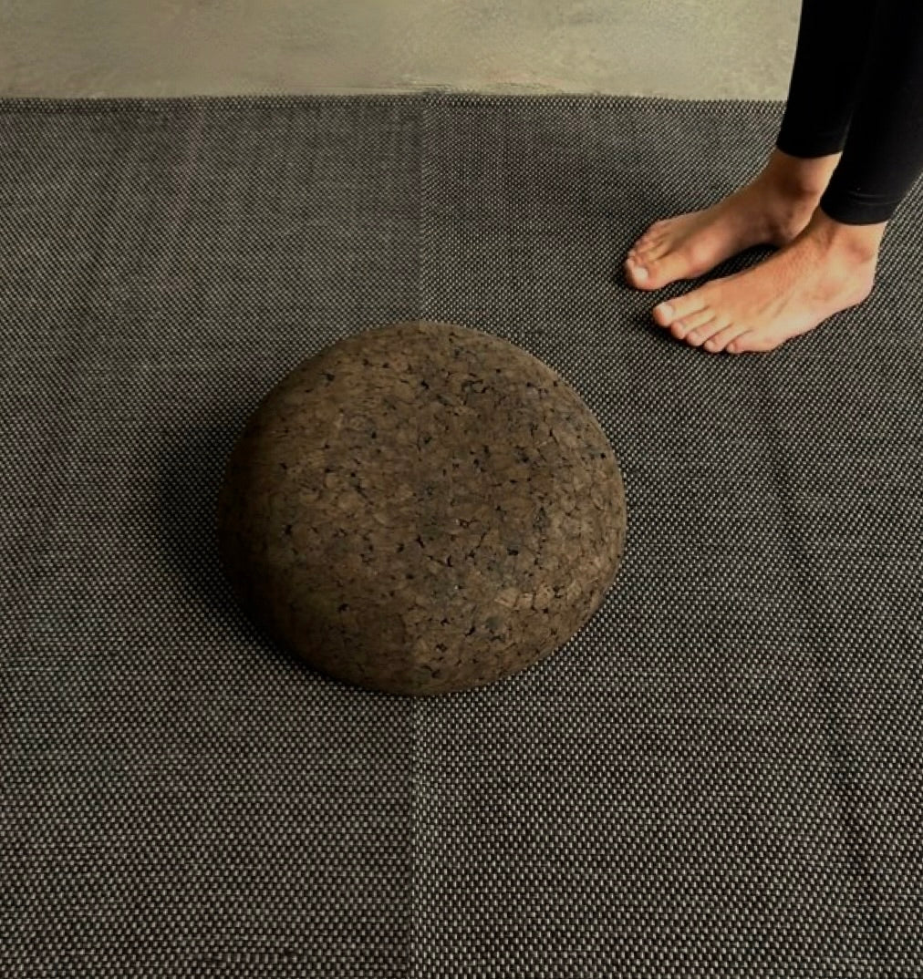 woman standing on cotton yoga rug with Rituil cork meditation seat sitting on top of it.