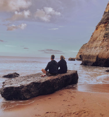 two men meditating on rock near ocean in Portugal
