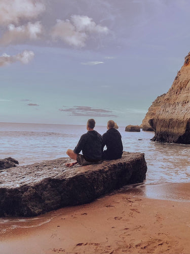 two men meditating on rock near ocean in Portugal