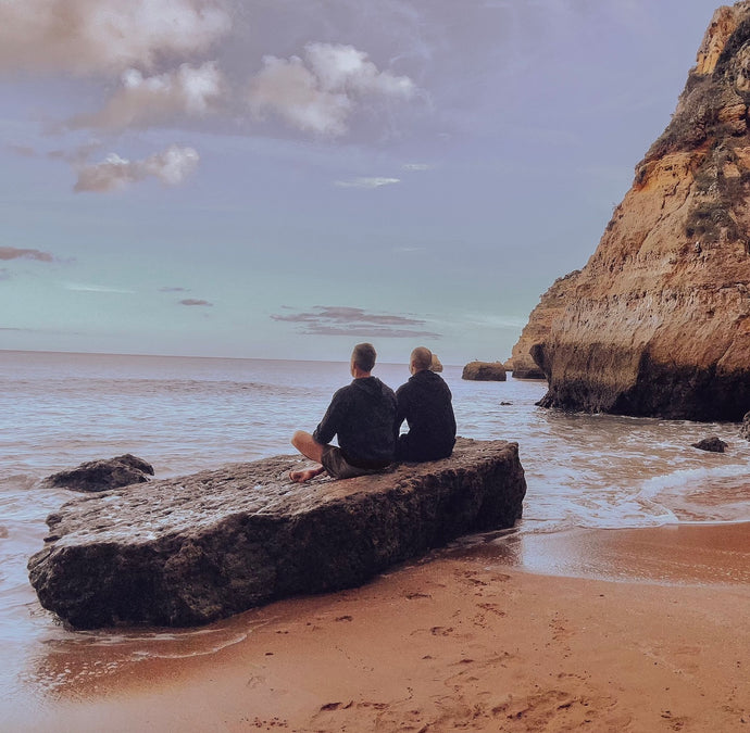 two men meditating on rock near ocean in Portugal