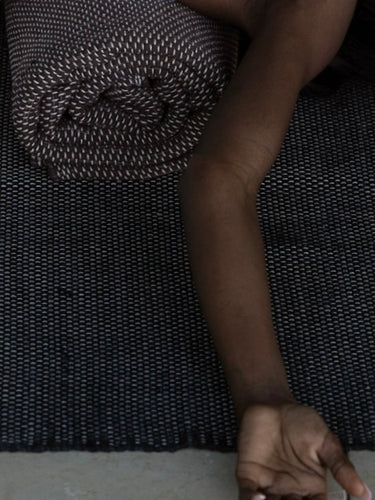 woman laying down on natural cotton yoga rug with hands