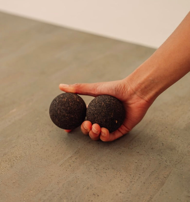 Rituil sustainable Portuguese cork massge balls for yoga, Pilates core workouts, and deep tissue muscle recovery shown with woman holding set in hand on top of cork yoga mat